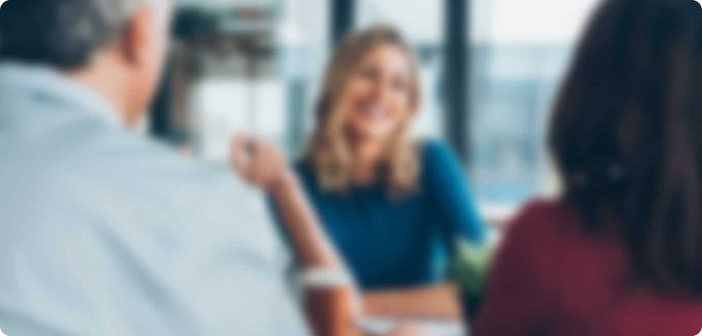 Three people are sitting at a table indoors, engaged in conversation; the photo is out of focus and their faces are not clear.