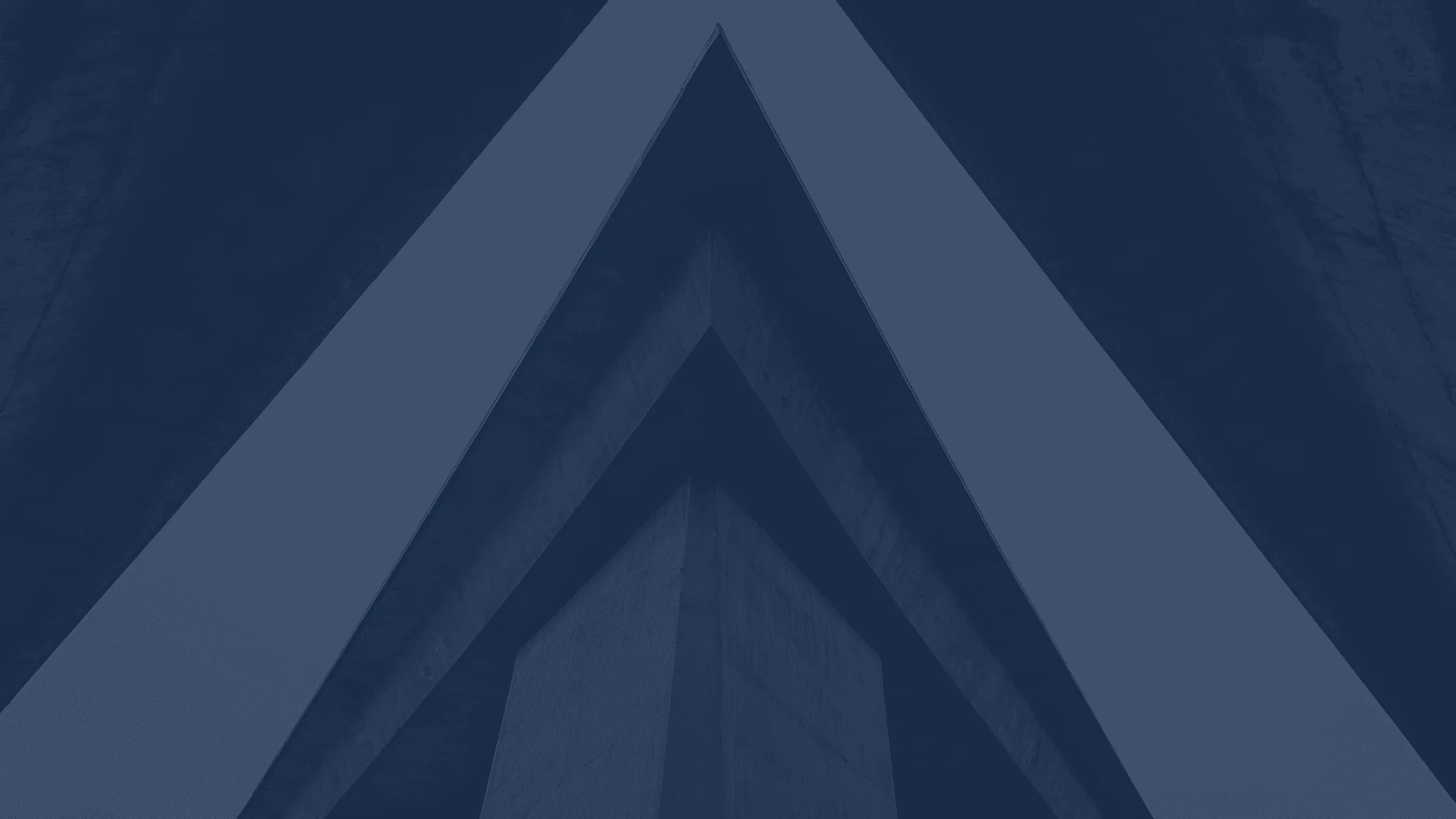 Abstract architectural image showing a low-angle view of intersecting concrete beams forming sharp geometric lines against a dark background.