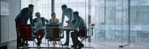 Five men and one woman conduct a strategy and operations consulting meeting at a small conference table.
