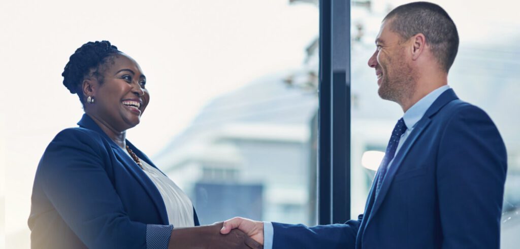 Two business leaders smiling and shaking hands after a successful post-merger integration strategy session