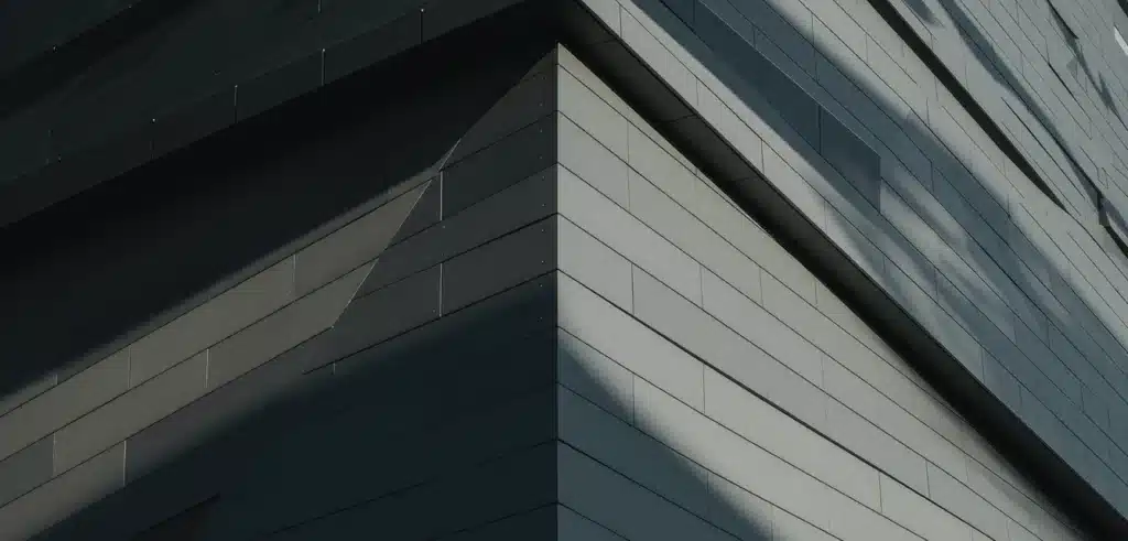 Close-up view of the sharp corner of a modern building with smooth, dark gray metal panels and geometric lines.