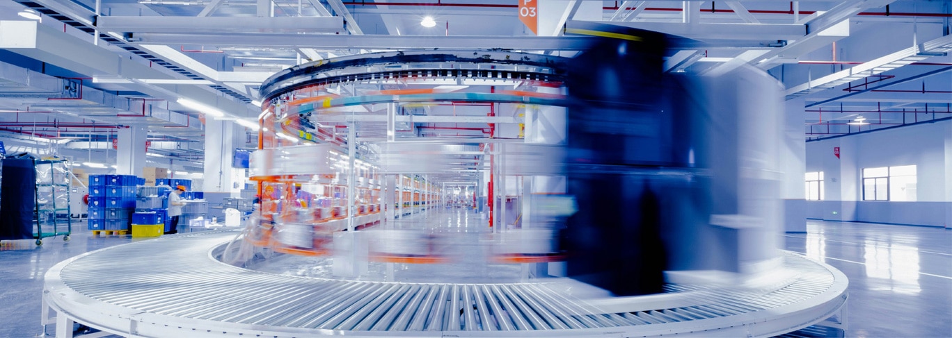 A conveyor system with blurred motion in a modern industrial facility, featuring automated machinery and bright overhead lighting.