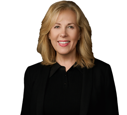 Woman with blonde hair wearing a black blazer and black top, smiling, posed against a plain white background.