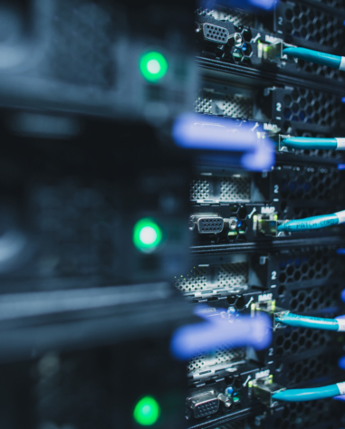 Close-up of server racks with blue ethernet cables and green indicator lights in a data center.