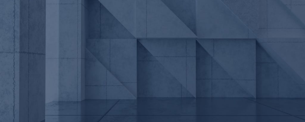 Geometric concrete wall with triangular and rectangular patterns in a blue-gray color, reflecting lightly on a polished floor.