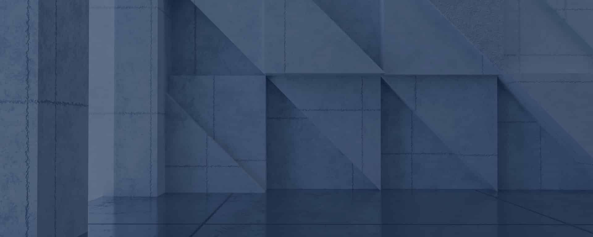 Geometric concrete wall with triangular and rectangular patterns in a blue-gray color, reflecting lightly on a polished floor.