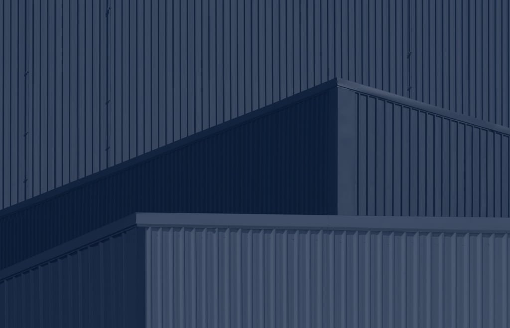 Close-up of a modern industrial building exterior featuring geometric shapes and vertical metal siding in a monochromatic blue color palette.